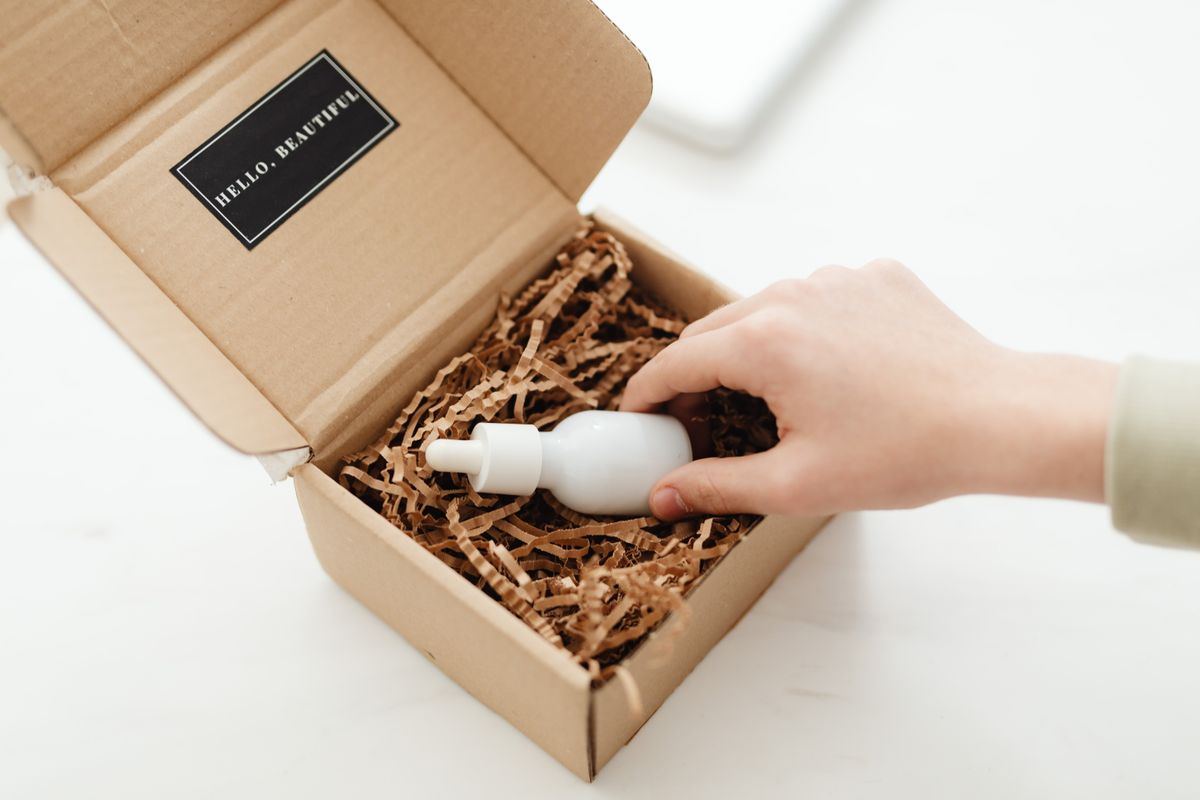 Hands unboxing a skincare bottle from a branded box